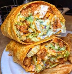 two burritos stacked on top of each other on a white plate with chips