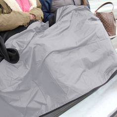 several people are sitting on a bench and one is holding a large piece of luggage