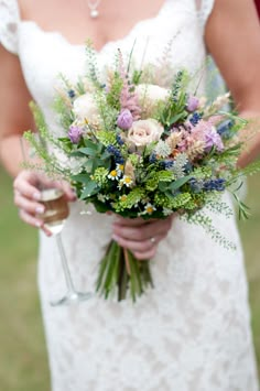 a bride holding a bouquet of flowers and a glass of wine in her left hand