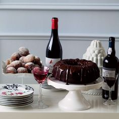 a table topped with plates and cakes next to bottles of wine, glasses and desserts