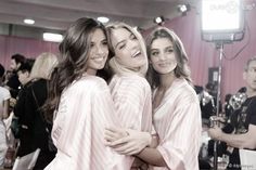 three women in pink robes standing next to each other and posing for the camera with their arms around one another