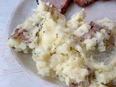 a white plate topped with mashed potatoes and meat