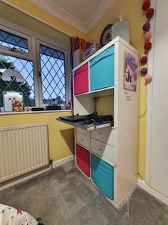 a computer desk with colorful drawers next to a window