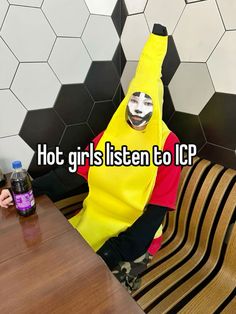 a person wearing a banana suit sitting at a table with a bottle of water in front of them