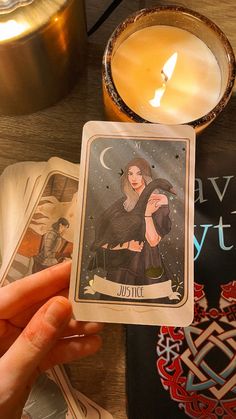 a person holding up a tarot card next to a candle