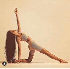 a woman is doing yoga on the floor with her legs spread out and hands in the air