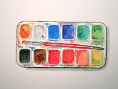 an artist's palette with watercolor paints and a brush