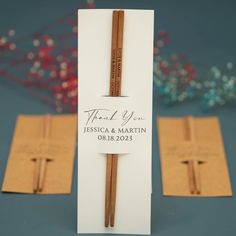 two wooden sticks are in front of a folded thank you card with a cross on it