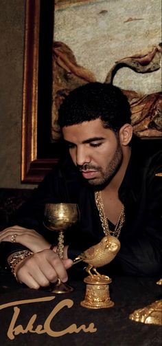 a man sitting at a table with a chalice in his hand and an oil lamp next to him