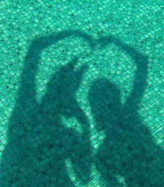 the shadow of a person holding a frisbee in front of a swimming pool