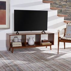 a flat screen tv sitting on top of a wooden entertainment center in a living room