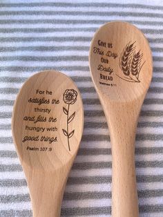 two wooden spoons with words on them sitting next to each other in front of a striped cloth