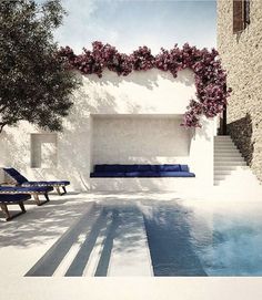 an outdoor swimming pool with lounge chairs and flowers growing on the wall next to it