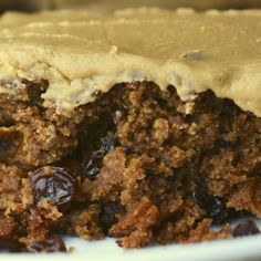 a piece of cake with frosting and raisins on it sitting on a plate