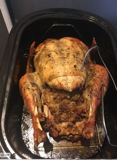 a roasting pan with a whole chicken in it and tongs sticking out of the side