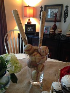 a glass vase filled with baseballs and cupcakes on top of a table