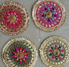 three colorfully decorated plates sitting on top of a white tile floor next to each other