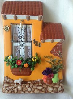 a yellow house with flowers and plants in the window sill on top of it