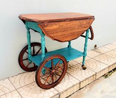 an old wooden cart with wheels is sitting on the sidewalk next to a white wall