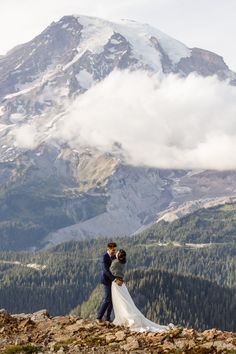 a bride and groom standing on top of a mountain