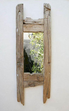 a mirror made out of wood on the side of a wall with plants in it