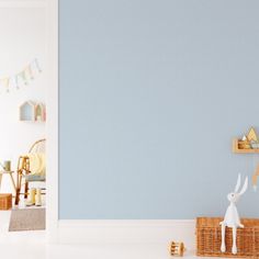 a white rabbit figurine sitting on top of a basket next to a blue wall