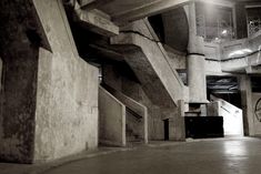 an empty room with stairs and clocks on the wall, in black and white photo