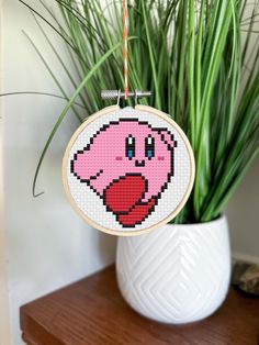 a cross stitch pig hanging from a plant