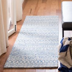 a blue and white rug sitting on top of a wooden floor next to a bench