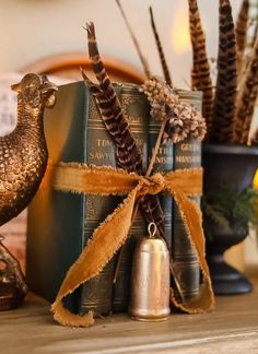 a bird figurine sitting on top of a table next to books and bells