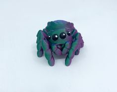 a purple and green spider toy sitting on top of a white surface