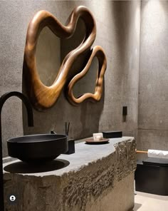 a bathroom with a sink, mirror and sculpture on the wall next to each other