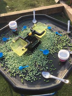 a tray filled with green peas and plastic spoons