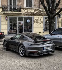 two porsches parked in front of a building on the side of a street with cars parked next to it