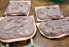 four trays filled with chocolate frosting on top of a wooden table