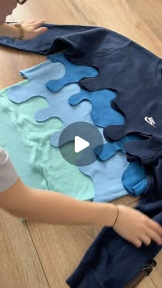 a doll is holding onto a shirt made out of pieces of blue and green fabric