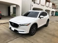 a white mazda cx - 5 parked in front of a building