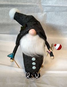 an odd looking gnome with white hair and black pants, holding two skis in his hands