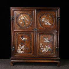 an old wooden cabinet with flowers painted on it's doors and handles, sitting against a black background