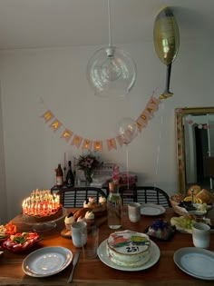 a wooden table topped with lots of plates covered in cake next to balloons and confetti