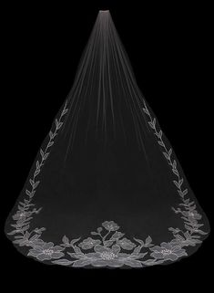 a wedding veil with flowers and leaves on the bottom, hanging from a black background