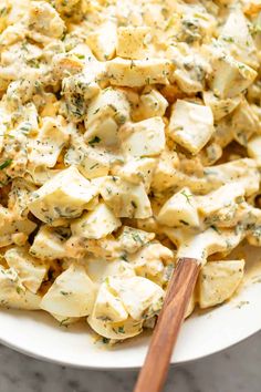 a white plate topped with potato salad and a wooden spoon