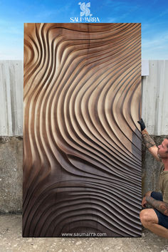 a man that is kneeling down next to a large piece of wood with waves on it