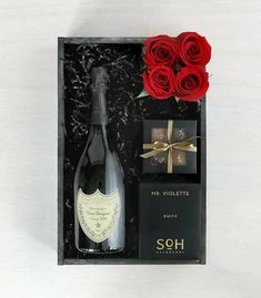 a bottle of wine and two red roses in a gift box for someone special occasion