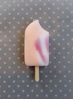 a popsicle with pink and white frosting on it sitting on a polka dot surface