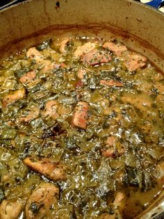 a pan filled with meat and greens on top of a stove