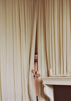 a woman peeking out from behind the curtains