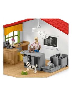 a doll house with a woman sitting at a desk and two cats on the floor