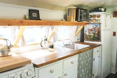 a kitchen with white cabinets and wooden counter tops, along with a stove top oven