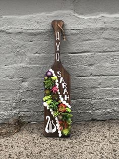 a wooden sign with succulents and flowers on the side of a building